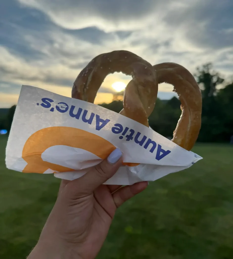 Food truck wedding nyc snack — hand holding a warm pretzel from Auntie Anne's