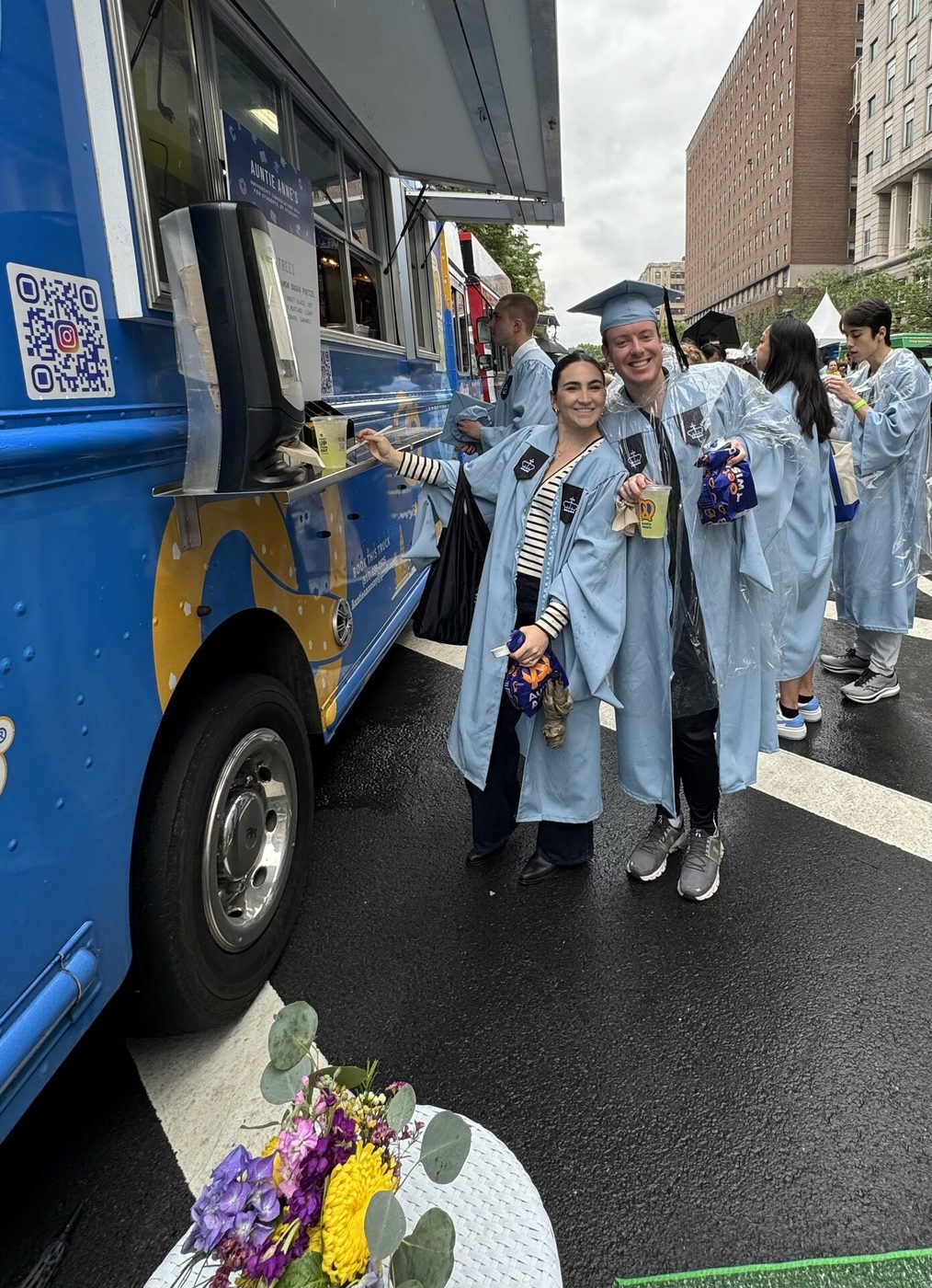 Two graduates smiling with drinks at the food truck window