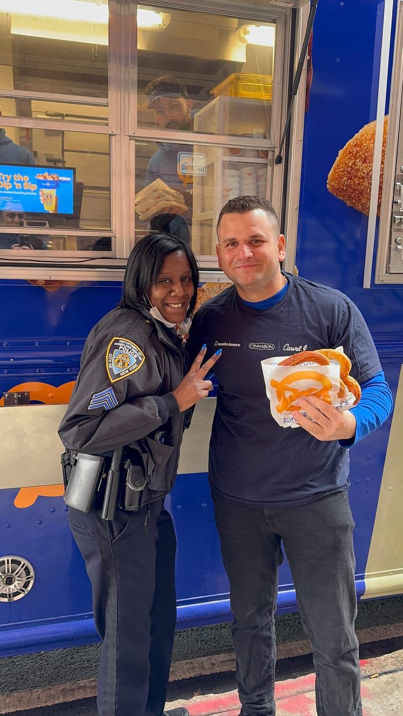 NYPD officer and Snack City NYC crew member sharing a pretzel